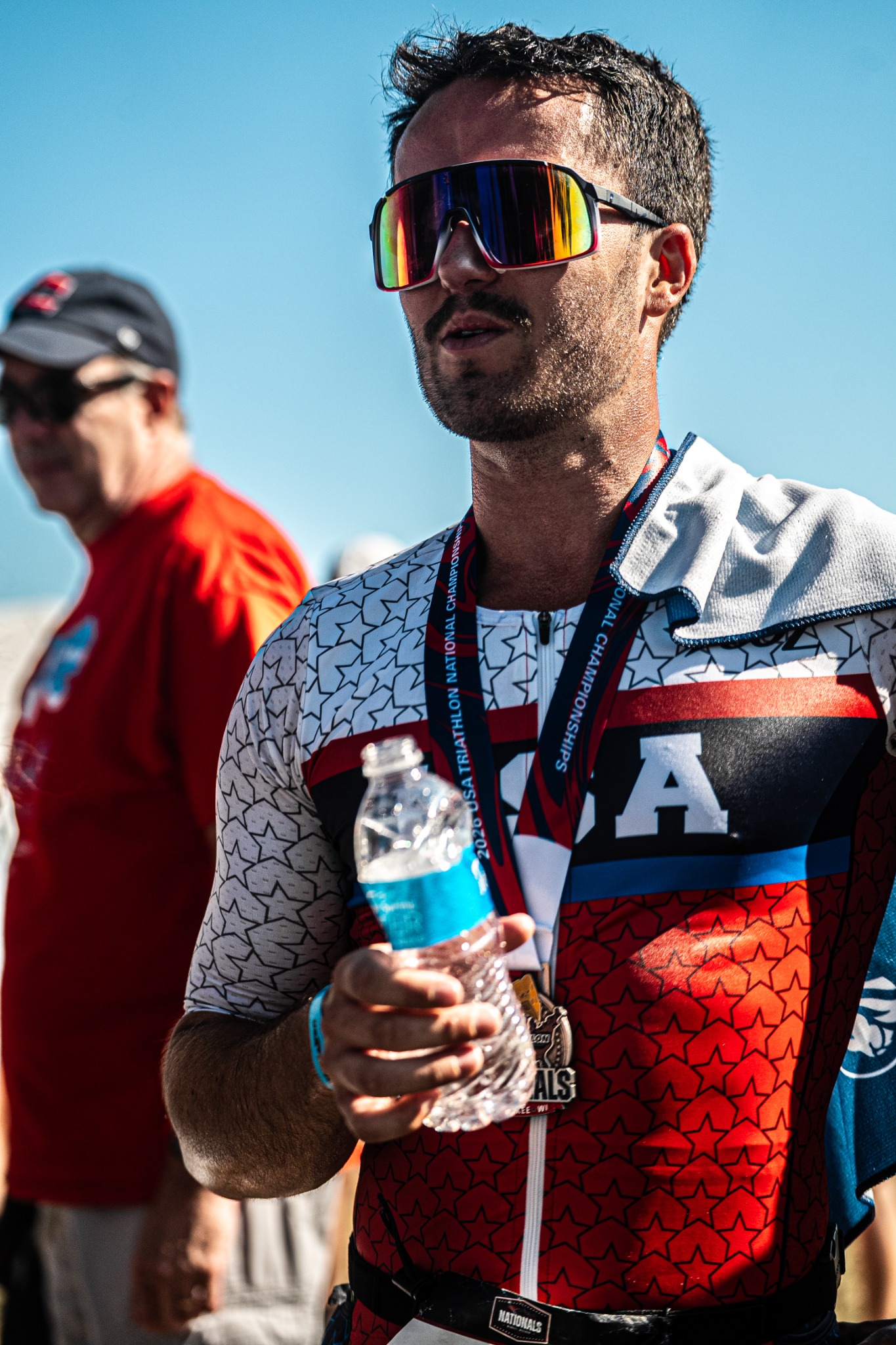 Triathlete wearing a finisher medal and mirrored sunglasses after competition
